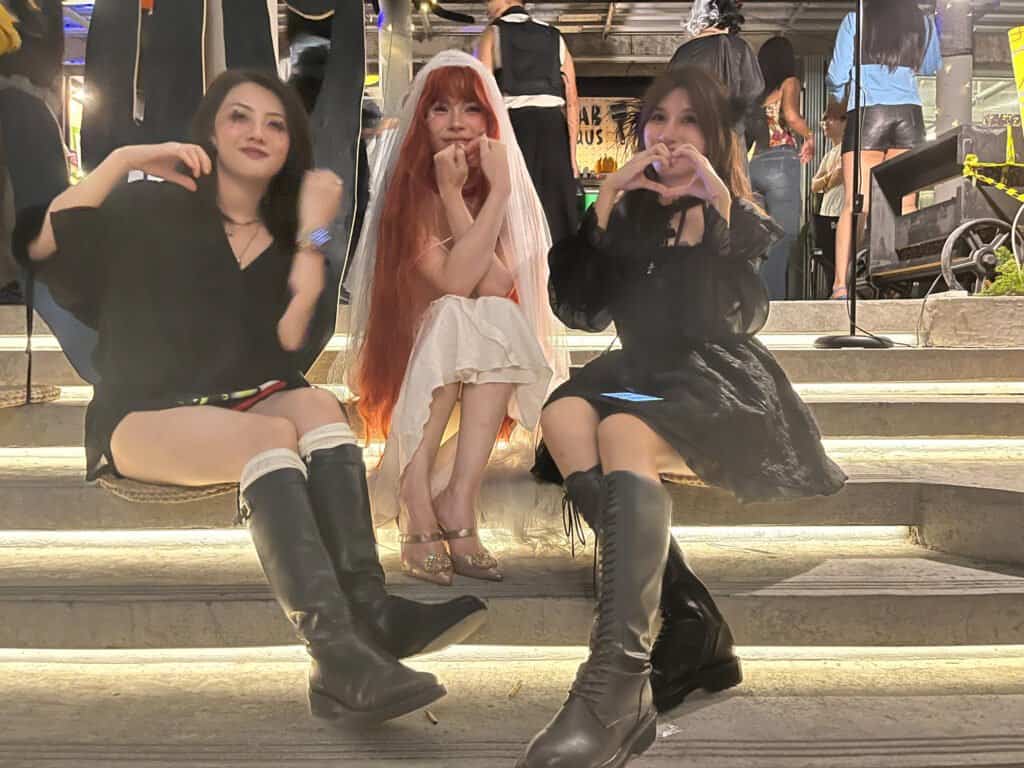 Dab haus Halloween three beautiful girls in fancy dress, sitting on steps amongst other customers, dressed up for Halloween