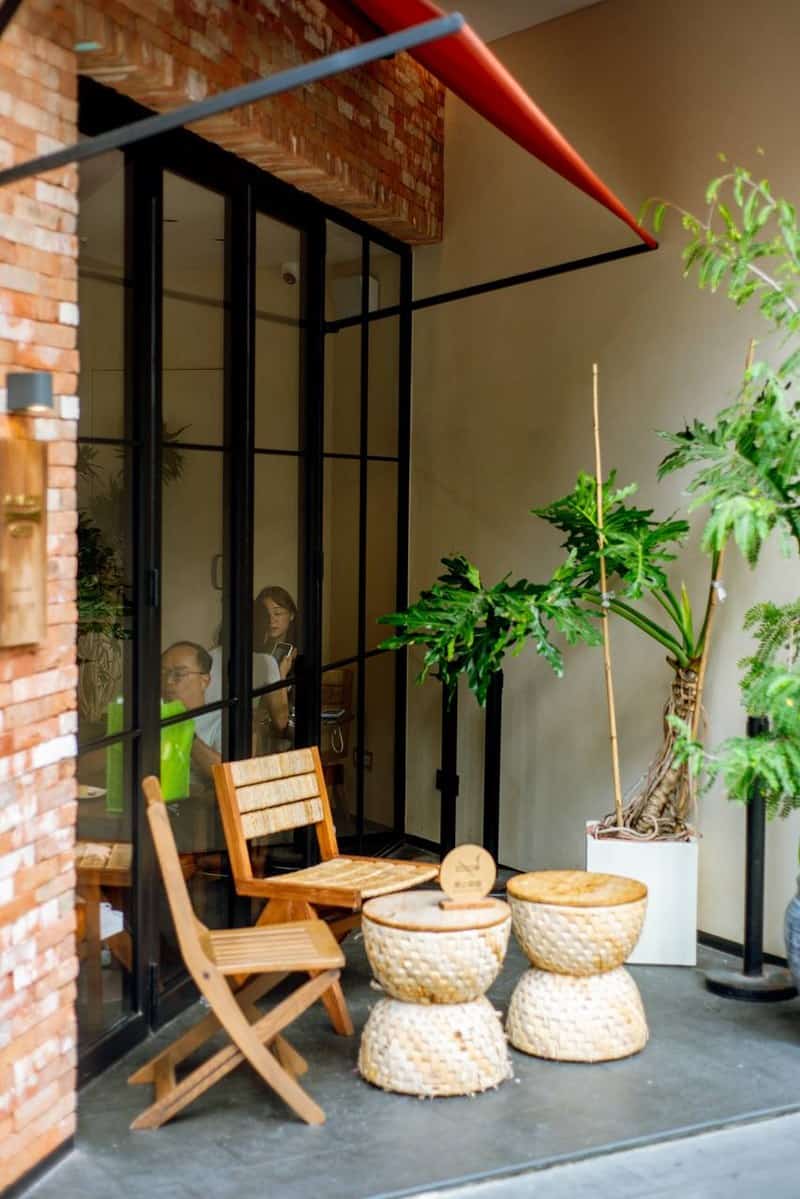 Walden's coffee patio with wooden chairs, round woven tables, and potted plants.