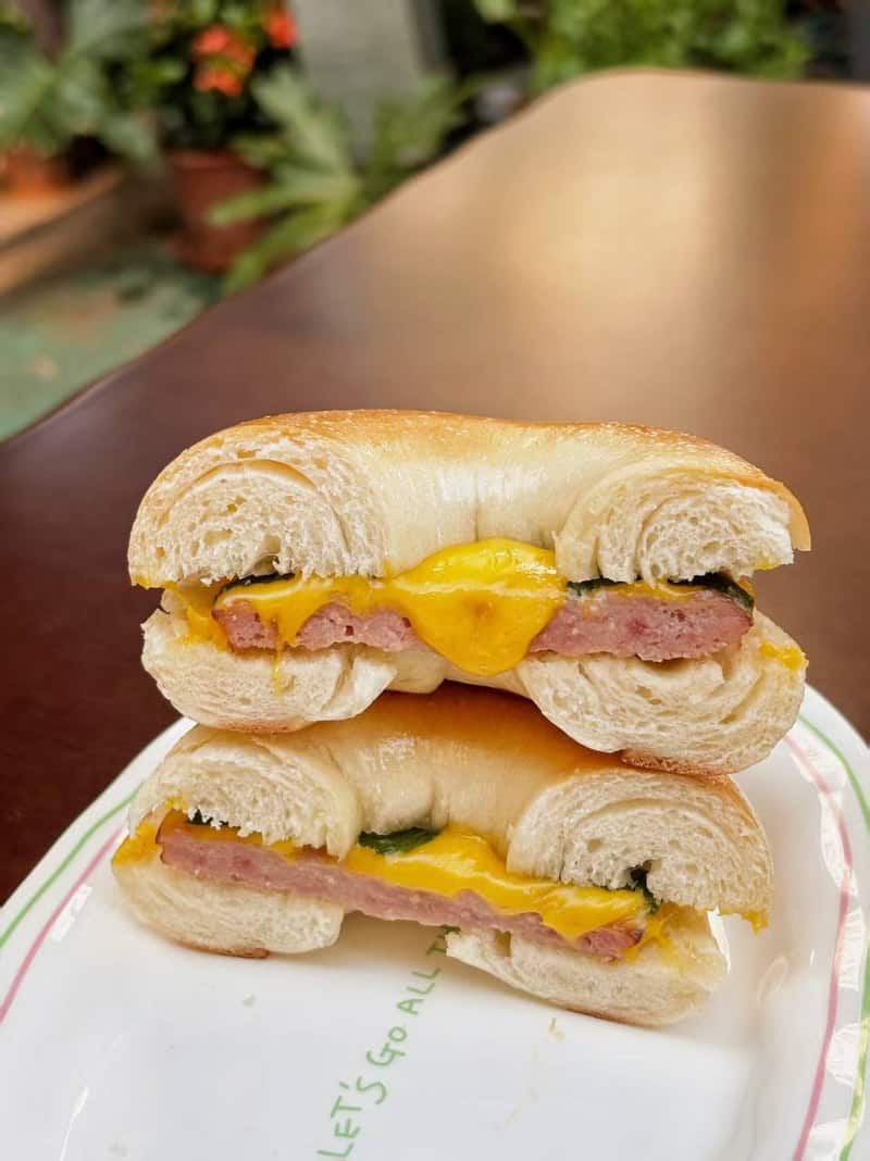 Stacked bagel sandwich halves with egg, melted cheese, and meat at Lotiko.