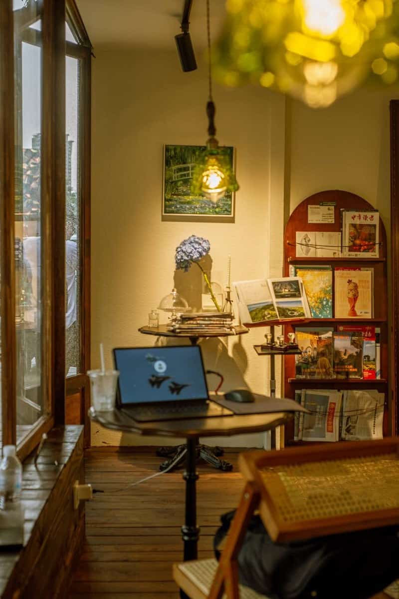 Interior corner at Lotiko with a laptop on a round table and a bookshelf with books and magazines in Chinese characters