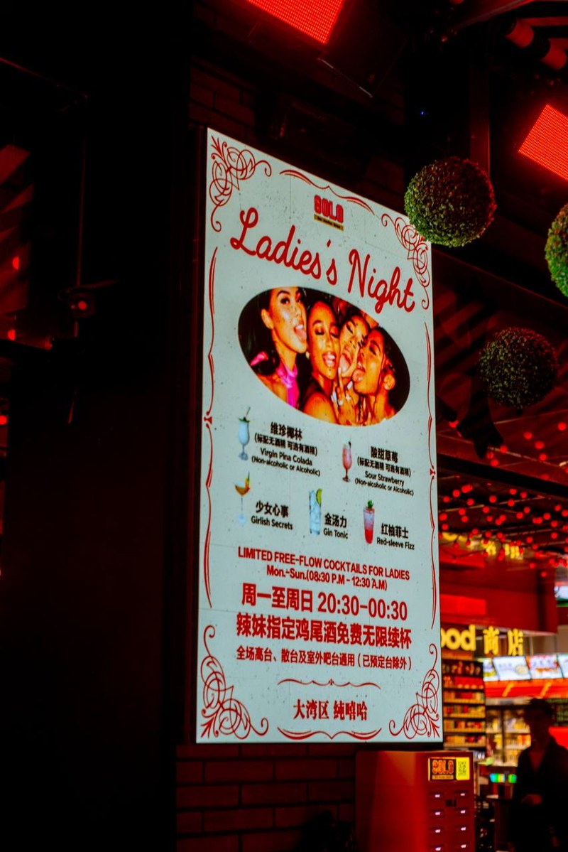 Illuminated ladies night sign at Scillia and Solo bar with green spheres and a silhouetted figure nearby — thirstyguide.com