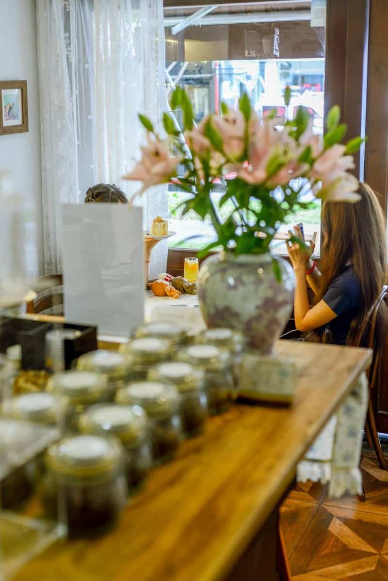 Jars, lilies, and guests by a window at Moon Ke Coffee (Moon可咖啡), Shenzhen coffee shop — thirstyguide.com