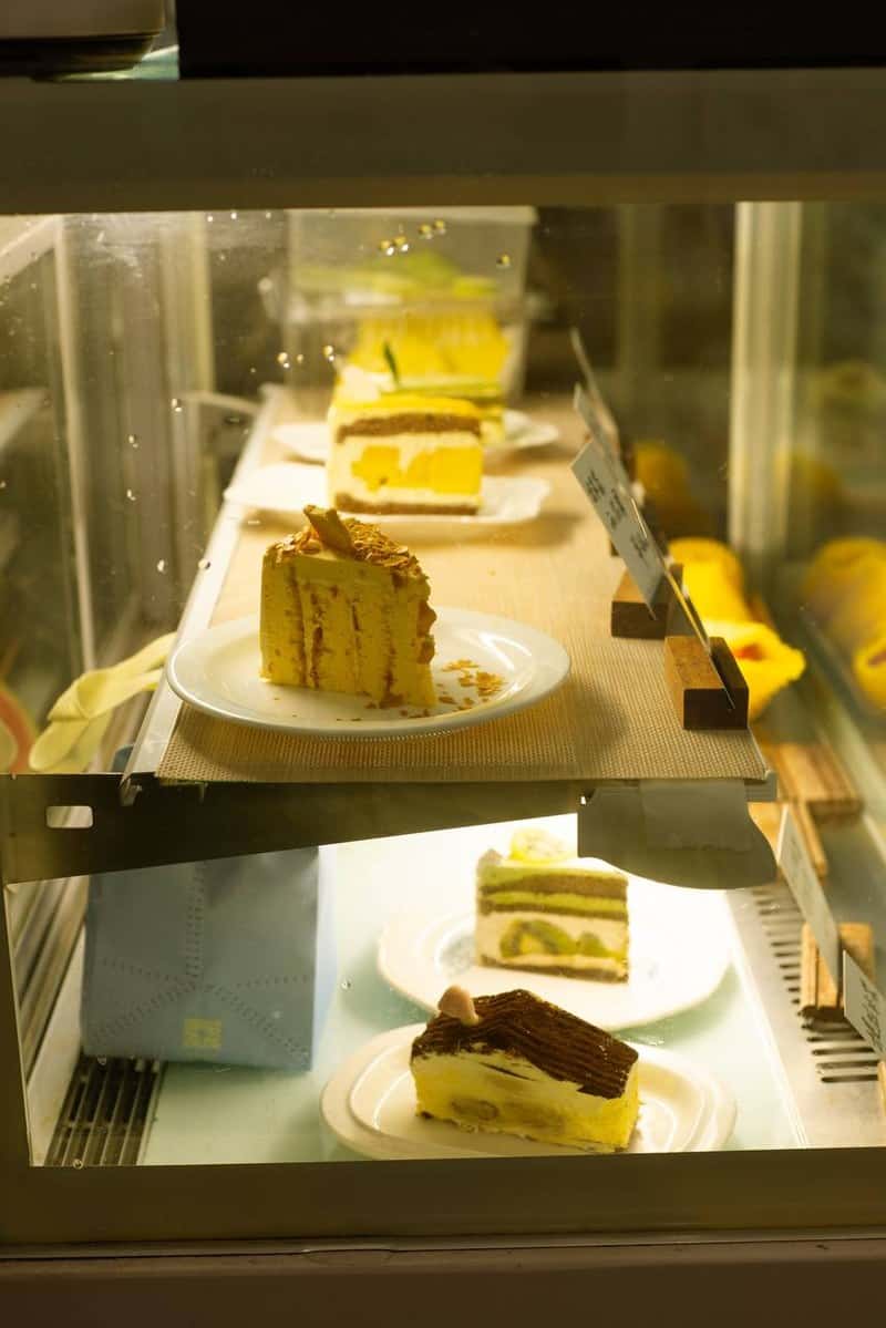 Layered cake on white plates behind glass at Moon Ke Coffee (Moon可咖啡) in Shenzhen, photographed for thirstyguide.com.