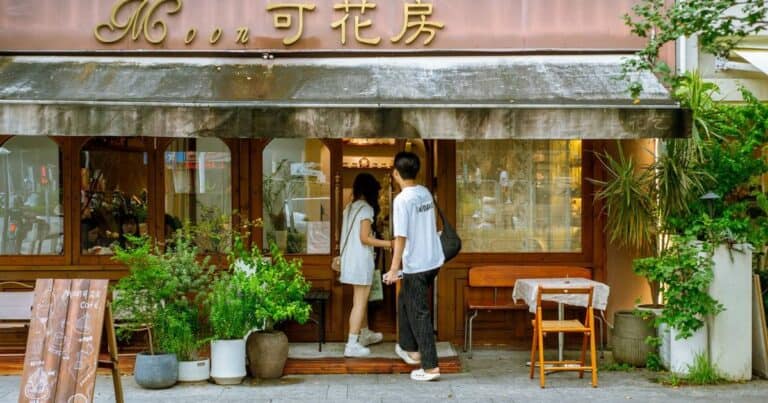 Two people at the entrance of Moon Ke Coffee (Moon可咖啡) in Shenzhen with a striped awning — thirstyguide.com
