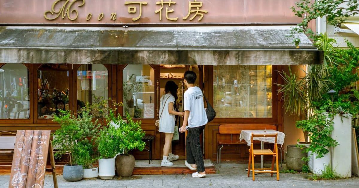 Two people at the entrance of Moon Ke Coffee (Moon可咖啡) in Shenzhen with a striped awning — thirstyguide.com